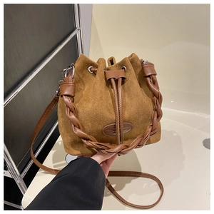 Detail of camel suede bucket bag featuring woven handle and drawstring closure