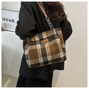 Detail of plaid wool tote bag featuring leather logo patch and silver chain strap
