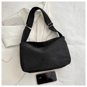 Detail of black rhinestone shoulder bag with adjustable strap on textured white fabric