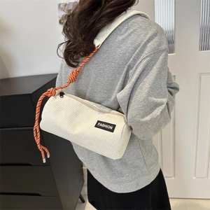White corduroy cylinder shoulder bag with orange woven strap shown on a female model