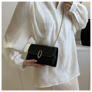 Detail of minimalist black crossbody bag with contrast stitching and golden clasp