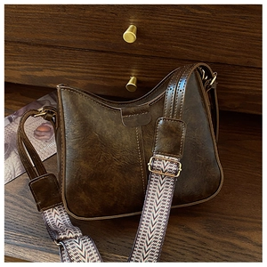 Detail of vintage brown leather handbag featuring a wide ethnic jacquard shoulder strap