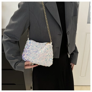 Close-up of iridescent sequin crossbody bag with gold chain strap on a model