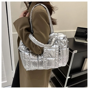 Close-up of a silver metallic quilted tote bag worn with a brown coat for winter style