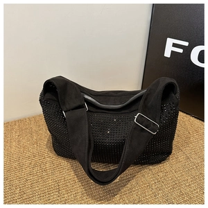 Detail of black suede shoulder bag with rhinestone embellishments and silver hardware
