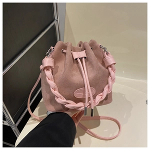 Detail of pink faux suede bucket bag with woven handle and drawstring closure