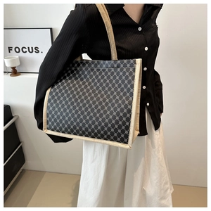 Detail view of large tote bag with geometric pattern held by a model in modern setting