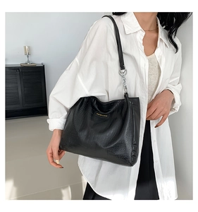 Detail of black faux crocodile skin tote bag featuring silver chain strap and metal logo