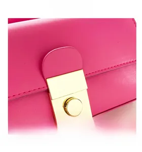 Macro shot of the golden rectangular twist lock on magenta leather textured bag