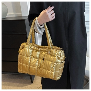 Detail of a shiny gold quilted tote bag featuring a matching small zipper pouch accessory