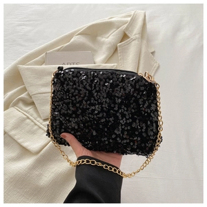 Close-up of black sequined evening clutch with gold chain strap and zipper closure