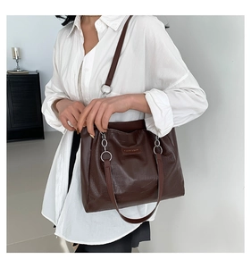 Close-up of brown crocodile pattern tote bag with silver chain detail on model