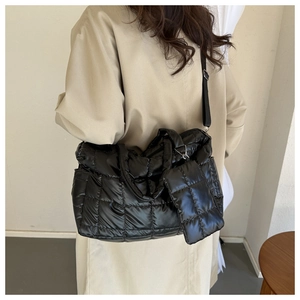 Close-up of black glossy quilted tote bag with padded texture and matching small pouch
