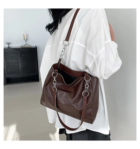Detail of dark coffee crocodile pattern tote bag with silver chain strap shown on shoulder