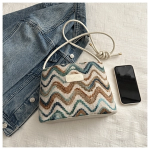 Detailed view of woven rainbow zigzag texture and leather label on the bucket bag