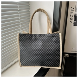 Detailed close-up of a structured tote bag with geometric pattern and woven beige handles