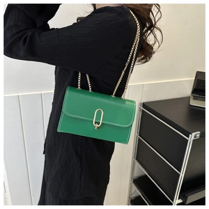 Detail of green crossbody bag with white stitching and oval gold metal lock clasp