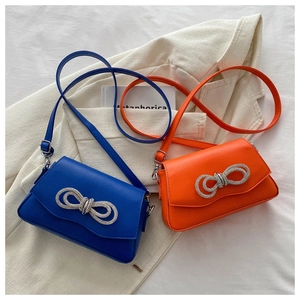 Détail de sacs bandoulière bleu et orange avec nœud en strass sur une veste élégante