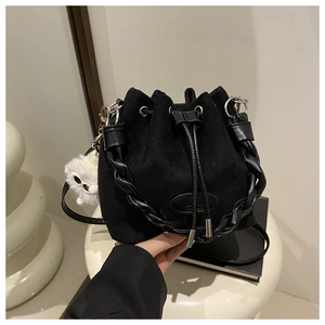 Detail of black suede drawstring bucket bag with woven handle and plush eye charm