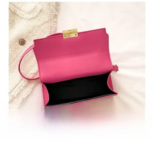 Detail view of the rose pink flap bag showing golden twist lock and internal compartment