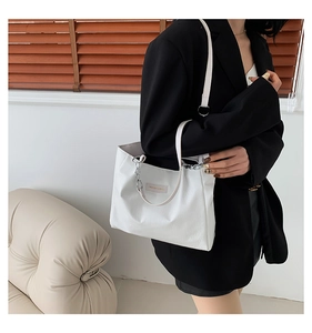 Detail view of white leather tote bag featuring metal chain and FASHION & BAGS logo