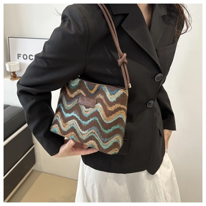 Detail of colorful chevron woven bag with brown leather logo and knotted shoulder strap