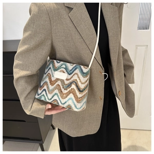 Detail of colorful woven shoulder bag with wavy stripes and white leather patch