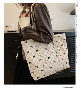 Fashionable corduroy shoulder bag with black diamond pattern and bow detail on a model