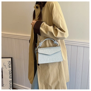 Detail of light blue glitter handbag showing the unique knotted handle and metallic texture