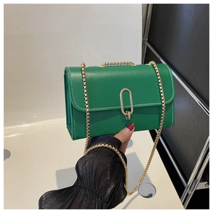 Detail view of green leather crossbody bag with white stitching and gold metal buckle