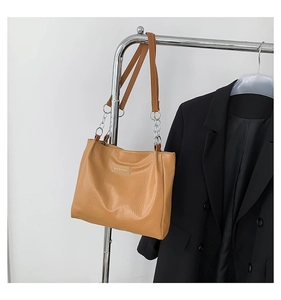 Detail of camel faux leather tote bag with crocodile texture and silver chain strap