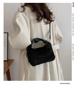 Detail of black faux fur hobo bag with leather handle and branded gold hardware