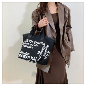 Black canvas tote bag with white Hawaii typography styled with a brown faux leather blazer