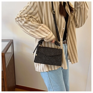 Detail of black glitter crossbody bag with knot shoulder strap and gold hardware
