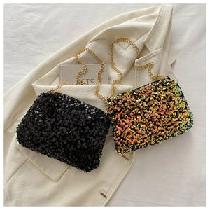 Close-up of shimmering sequin crossbody bags with gold chain straps on textured fabric