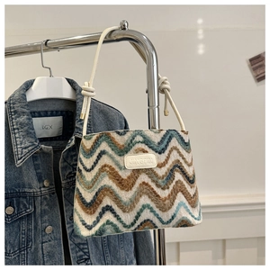 Detail of striped knitted bucket bag with blue waves and leather brand tag