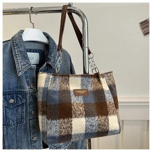 Detail of wool plaid tote bag with brown leather handles and silver chain connectors
