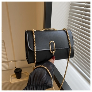 Close-up of black crossbody bag with contrast stitching and golden oval metal lock