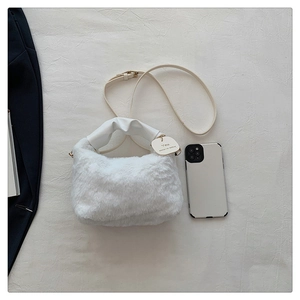 Close-up of white faux fur handbag with leather strap and decorative oval tag detail