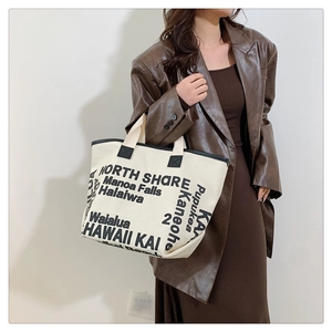 Close-up of canvas tote bag with black letter print and premium faux leather trim