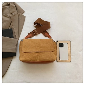 Detail of ginger yellow faux suede handbag with adjustable brown woven shoulder strap
