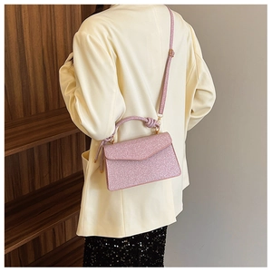 Detailed shot of pink sequin crossbody bag with knot handle decoration and gold hardware
