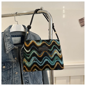Macro detail of wave-pattern woven tote bag with leather logo patch and rope handles