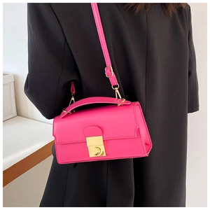 Detail of hot pink crossbody square bag with gold lock buckle on black blazer