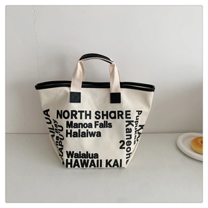 Macro shot of durable white canvas tote bag with bold black typography and sturdy straps
