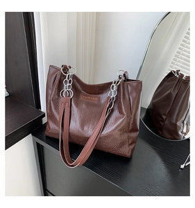 Close-up of brown crocodile pattern tote bag with silver chain strap and metal logo