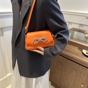 Sac bandoulière orange chic avec nœud en strass argentés sur tenue de printemps élégante