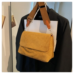 Detail of ginger yellow faux suede crossbody bag with wide strap and gold hardware