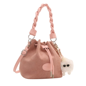 Pink suede bucket bag with woven handle, drawstring closure, and cute monster pendant