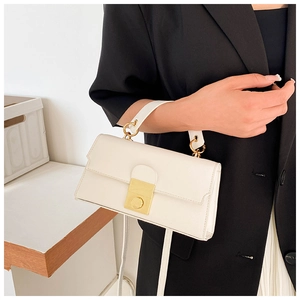 Close-up of a white textured leather crossbody bag with a golden square twist lock buckle